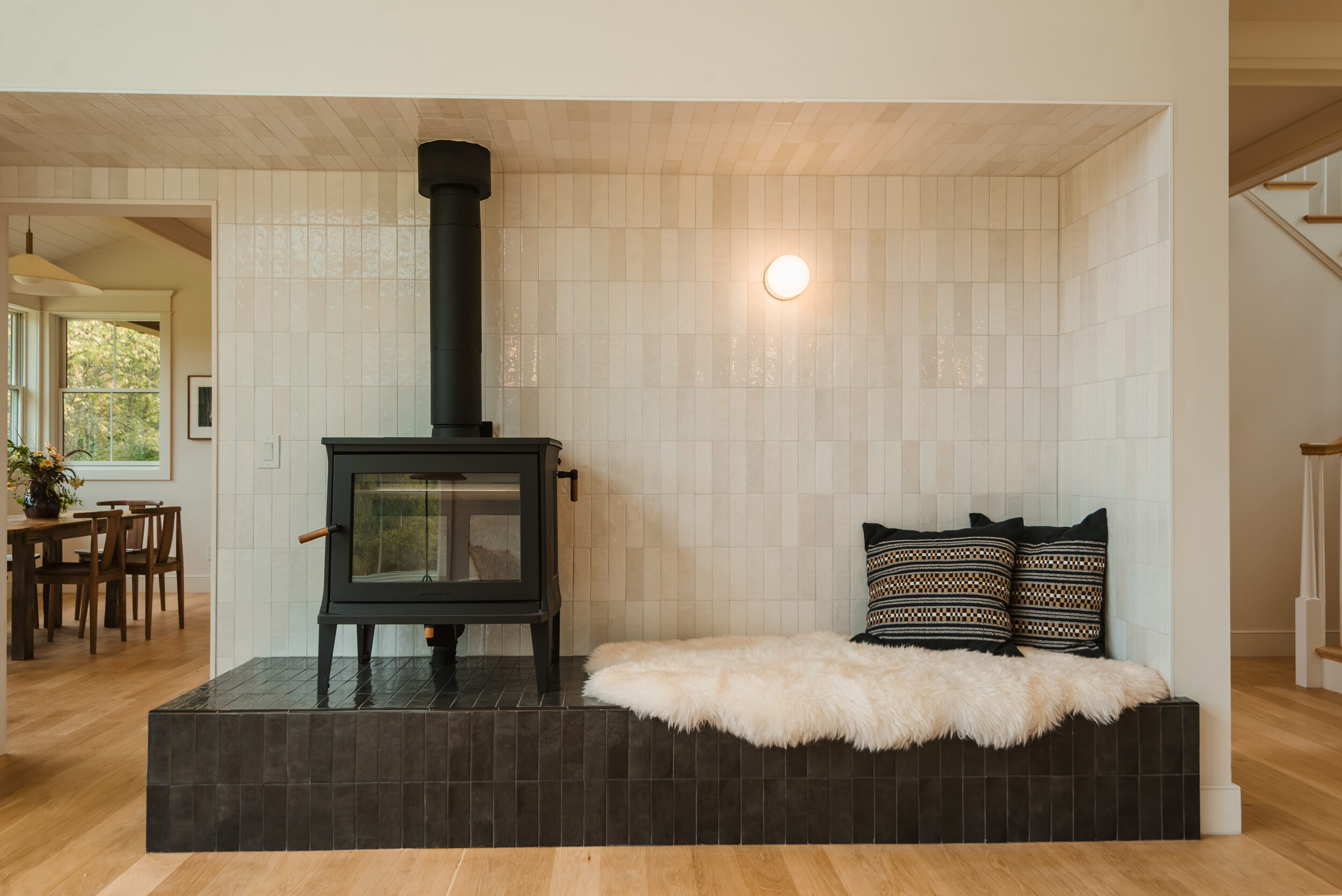 Hemlock House — wood stove set into a tiled alcove with built-in bench